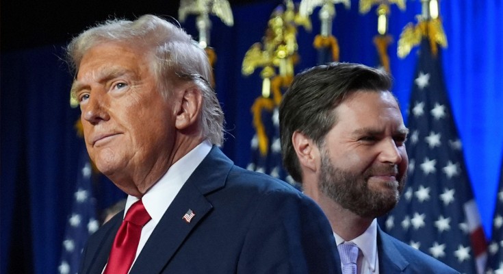 Donald Trump and J. D. Vance standing on a stage in front of American flags