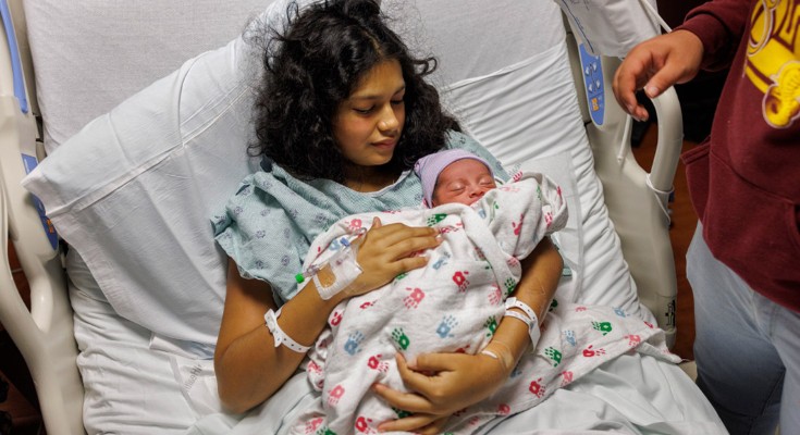 A woman lies in a hospital bed holding a baby