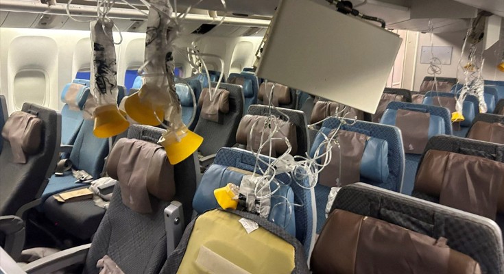 Interior of the Singapore Airlines flight, the seats empty. Oxygen masks are hanging down and pillows are scattered in disarray. Bits of the plane ceiling are hanging down
