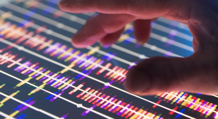 Close up view of a researcher's hand interacting with a DNA sequence on a digital display