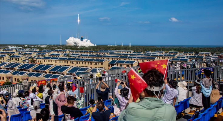 Spectators with flags take photos as a Long March-8A carrier rocket carrying a group of low Earth orbit satellites blasts off in China
