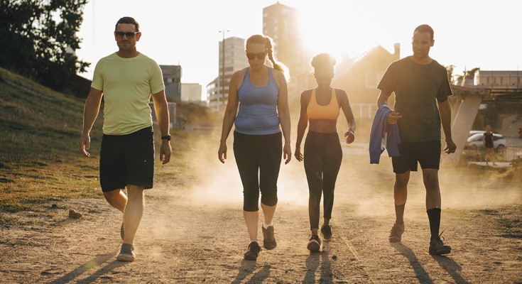 Four people in workout gear walk towards the camera