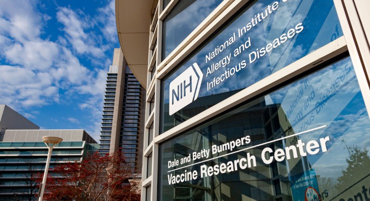NIH glass building exterior with signage for the National Institute of Allergy and Infectious Diseases and Vaccine Research Center, on a sunny day