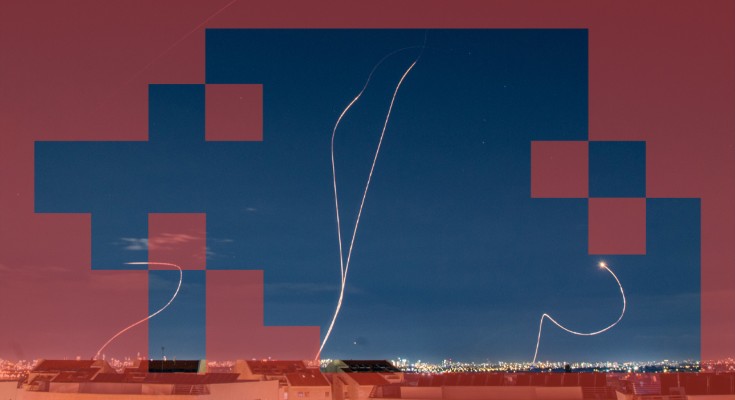 Streaks of light show the path of missiles above a city at night
