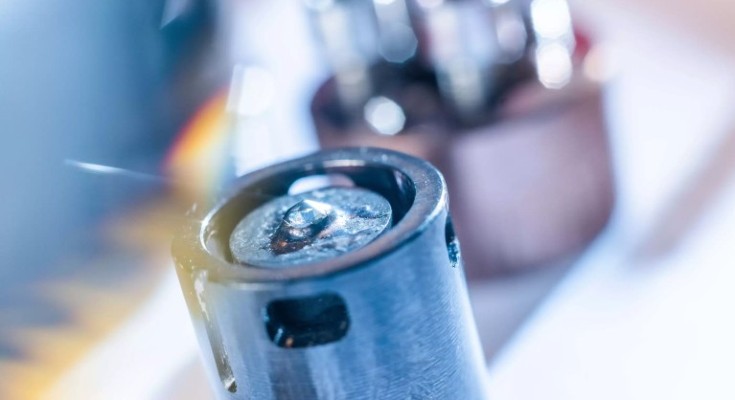 Superconductivity apparatus; image shows a cylindrical piece of metal, with other equipment blurred in the background