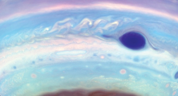 A dark purple oval is visible in the southern hemisphere of Jupiter, which itself is rendered in unusual colours: pinks and lilacs and blues and burgundy.