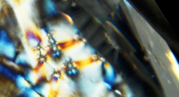 Vivid colours of purple, white, and blue observed in a close up of diamond inclusions.