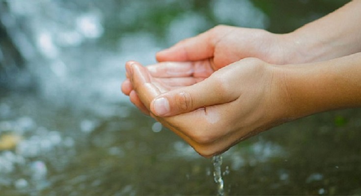 Hands lifting water from a stream
